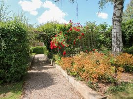 A garden with a pathway surrounded by flowers and greenery at Uplands Cottage Ledbury