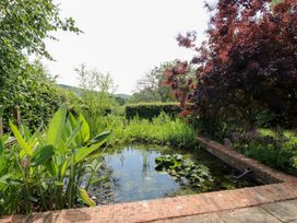 A garden with a pond and various plants at Uplands Cottage in Ledbury