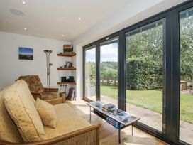 A living room with a sofa and sliding door to the garden at Garden Cottage Wellington Heath near Ledbury