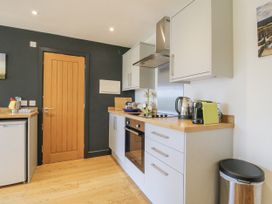 A kitchen with appliances and wooden door at Garden Cottage in Wellington Heath near Ledbury