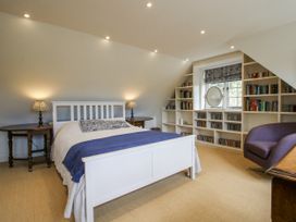 A bedroom with a bed, bookshelf, and chair at Garden Cottage in Wellington Heath near Ledbury