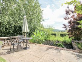 A garden with a table and chairs under an umbrella at Garden Cottage Wellington Heath near Ledbury