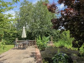 A garden with a table and chairs and a pond at Garden Cottage in Wellington Heath near Ledbury