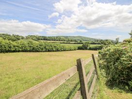 A field with a wooden fence and trees at Garden Cottage in Wellington Heath near Ledbury