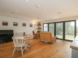 A living room with a piano, table, and sofa at Garden Cottage Wellington Heath near Ledbury
