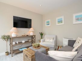 A living room with a television and seating area at Evelyn in Looe