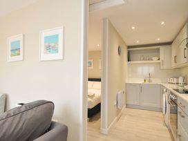 A living room with a kitchen and bed visible at Evelyn in Looe