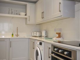 A kitchen with cabinets, sink, kettle, and washing machine at Evelyn in Looe