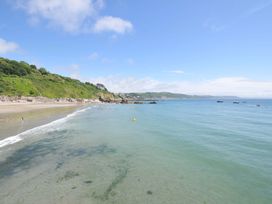 A beach with people swimming and boats in the ocean at Evelyn in Looe