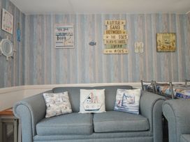 A living room with a blue sofa and decorative pillows at 13 Hillside in Bude