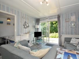 A living room with a television and sliding door at 13 Hillside in Bude
