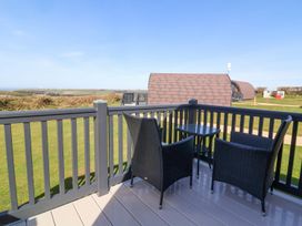 A deck area with chairs and a table overlooking a green landscape at New Pod Kilkhampton