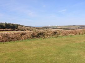 A grassy outdoor area with bushes and trees overlooking the ocean at New Pod Kilkhampton