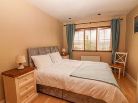 A bedroom with a bed, nightstand, lamp, window, and a chair at 51 Woodview Park in Tralee, County Kerry