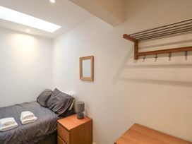 A bedroom with a bed, table, lamp, and shelf at Chestnut Cottage in Bridlington