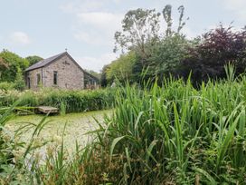 A house near a pond surrounded by plants at The Dovecote Llanychaer near Fishguard