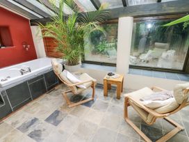 A conservatory with a bathtub and seating area at The Dovecote Llanychaer near Fishguard