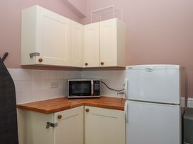 A kitchen with cabinets, a microwave, and a fridge at Captains Cottage in Brixham