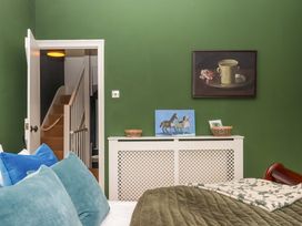 A bedroom with a green wall and a staircase at Captains Cottage in Brixham