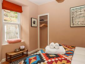 A bedroom with a bed and shelves at Captains Cottage in Brixham