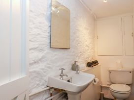 A bathroom with a sink, toilet, and mirror at Captains Cottage Brixham