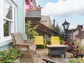 A garden with wooden and yellow chairs and a table at Captains Cottage in Brixham