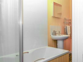 A bathroom with a bath tub and sink at Captains Cottage in Brixham
