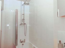 A bathroom with a bathtub and shower fixture at Captains Cottage in Brixham