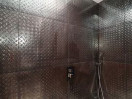 A shower with metallic tiles and a showerhead at Noflash Malpal in Bristol