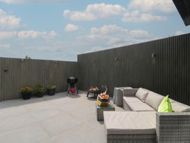 An outdoor terrace with a sofa and grill at Noflash Malpal in Bishop Sutton