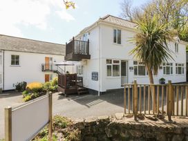 An outdoor view of a house with a balcony and decking at Tater-Du in Porthcurno