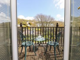 A balcony with two chairs and a table at Tater-Du in Porthcurno