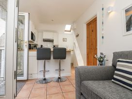 A kitchen with bar stools and a glass door at Tater-Du in Porthcurno