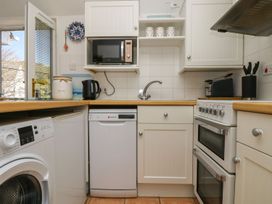 A kitchen with appliances including a washing machine and microwave at Tater-Du in Porthcurno