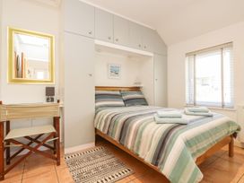 A bedroom with a bed and a mirror at Tater-Du in Porthcurno