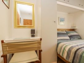 A bedroom with a bed and a mirror at Tater-Du in Porthcurno