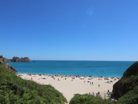 A beach with people sunbathing and swimming at Tater-Du in Porthcurno