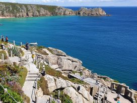 A scenic view with people along a pathway near the sea at Tater-Du in Porthcurno near Land’s End