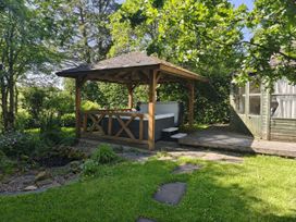 A garden with a wooden gazebo and hot tub at Bush Nook House in Brampton, Cumbria
