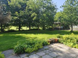 A garden with trees and a gazebo at Bush Nook House in Brampton, Cumbria