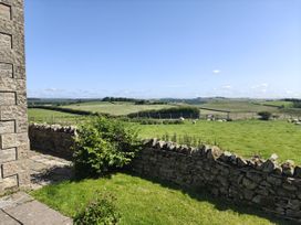 A view of the countryside with a stone wall and grass at Bush Nook House in Brampton, Cumbria