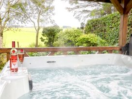 An outdoor hot tub with wine glasses and a bottle at Bush Nook House in Brampton, Cumbria