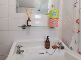 A sink and mirror with soap and decorative items at Moot Cottage in Driffield