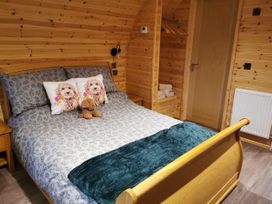 A bedroom with a wooden bed and decorative pillows at Lodge 1 Pontyates