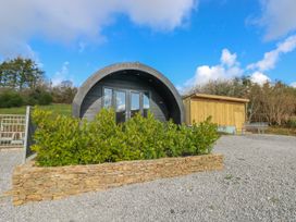 A pod and wooden shed with a stone wall and plants at Lodge 1 near Pontyates