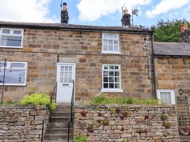 A house with windows and a door in front of a stone wall at 5 Hollins Cottages Whitby
