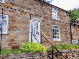 The front facade of a cottage with a white door and stone walls at 5 Hollins Cottages, Whitby
