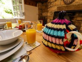 A dining table set for breakfast with juice, fruit, and a teapot at 5 Hollins Cottages in Whitby