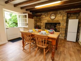 A kitchen with a table and chairs in front of a stone fireplace at 5 Hollins Cottages in Whitby