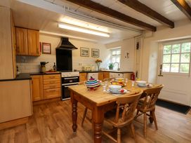 A kitchen with wooden cabinets and a dining table at 5 Hollins Cottages Whitby